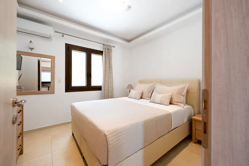 A double bedroom with a mirror and shuttered window