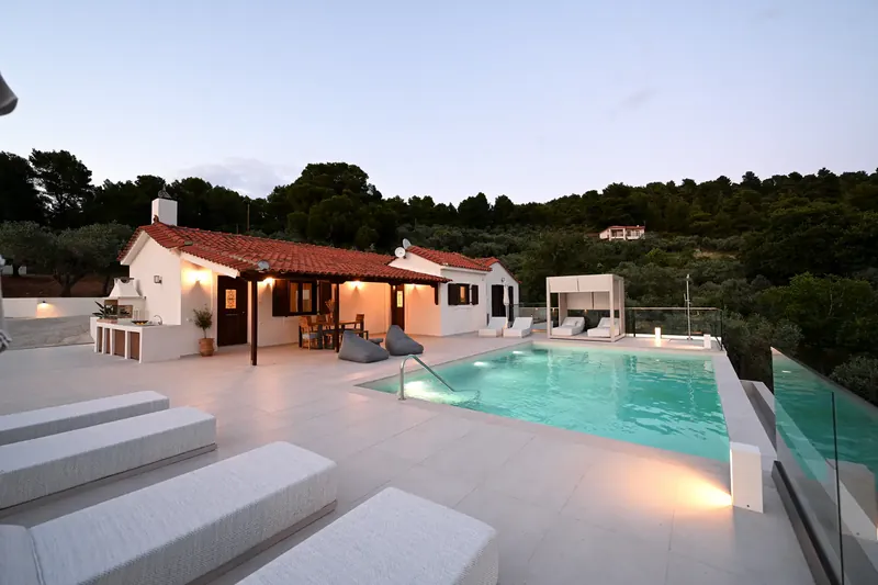 The villa lit beside its pool at dusk